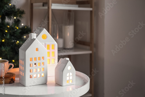 House shaped candle holders and cup of coffee on table in living room, closeup