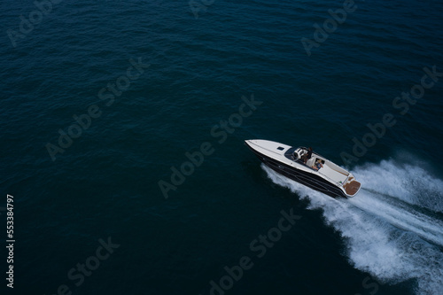 Large high-speed boat White blue colors fast movement on the water top view. Aerial view of the sea and the boat.