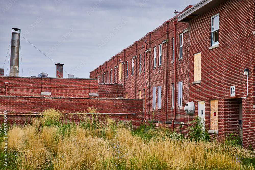 Exterior of abandoned brick buildings with overgrown fields