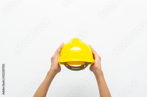 Male hand holding yellow safey hard hat isolated over white background. work safety concept. labour day concept.	
