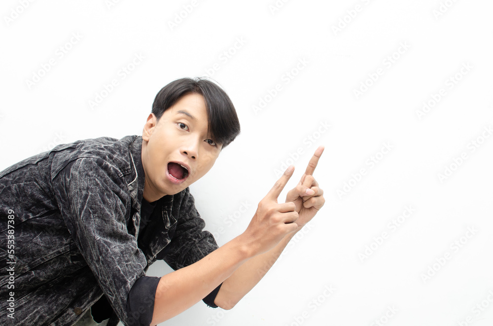 Happy Ecstatic asian man wear jeans jacket pointing finger to copy space presenting and showing goods. billboard model advertisment concept. man with wow face showing something. Happy Ecstatic asian man wear jeans jacket pointing finger to copy space presenting and showing goods. billboard model advertisment concept. man with wow face showing something.