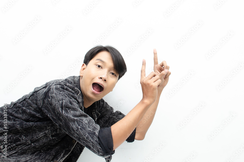 Happy Ecstatic asian man wear jeans jacket pointing finger to copy space presenting and showing goods. billboard model advertisment concept. man with wow face showing something. Happy Ecstatic asian man wear jeans jacket pointing finger to copy space presenting and showing goods. billboard model advertisment concept. man with wow face showing something.