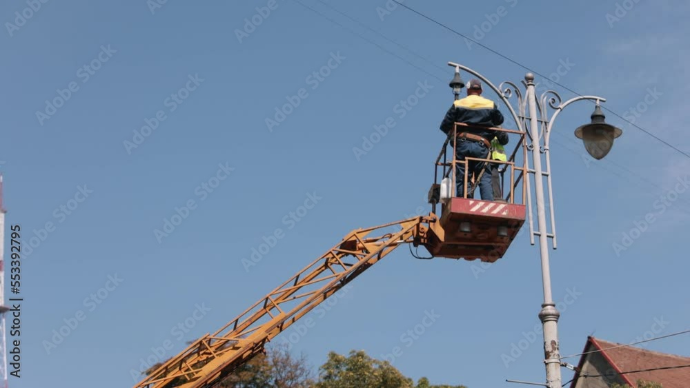 street lamp, repair works, led lights. Street light repair works are carried out, worker repairing street light at height, replacing led light, men in lift buckets fixing pole lamps street lamp, repair works, led lights. Street light repair works are carried out, worker repairing street light at height, replacing led light, men in lift buckets fixing pole lamps