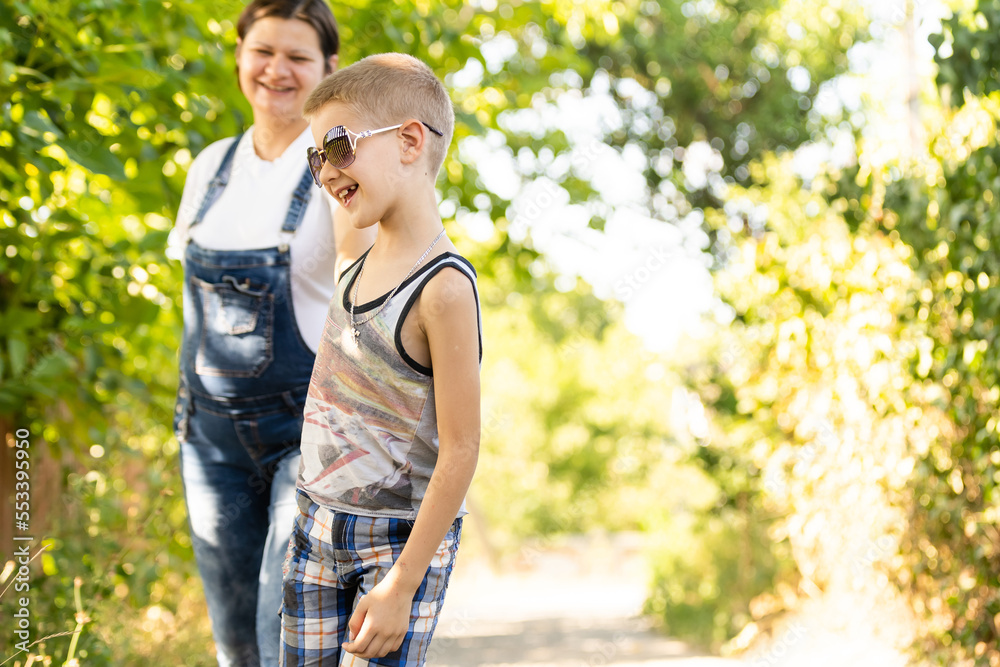 Fototapeta premium Pregnant woman walking countryside with her son. Child hugging his pregnant mother.