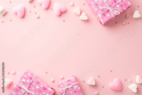 Valentine's Day concept. Top view photo of gift boxes heart shaped marshmallow candles and sprinkles on isolated light pink background with empty space © ActionGP