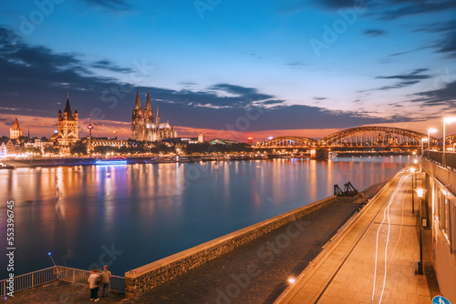 Night view of the Rhine embankment in Cologne. Urban life in Germany. Koln Cathedral in the background