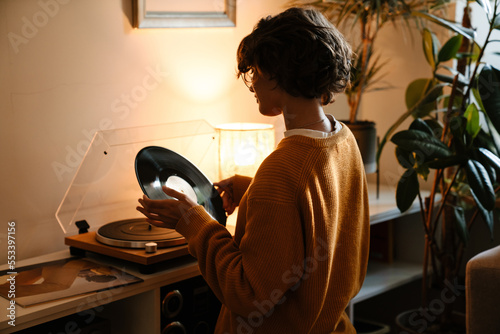 Obraz na plátně Brunette young woman in eyeglasses using stereo turntable