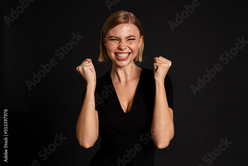Young blond woman smiling and making winner gesture