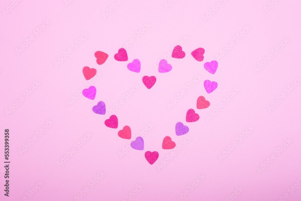 Heart-shaped frame made of small hearts on a pink background. The concept of Valentine's day, love, dating and wedding. Symbol of a romantic gift or marriage proposal. Copy space, minimalism.