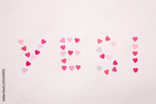 The word yes and an exclamation mark made from hearts on a gray background. The answer is yes to a marriage proposal.