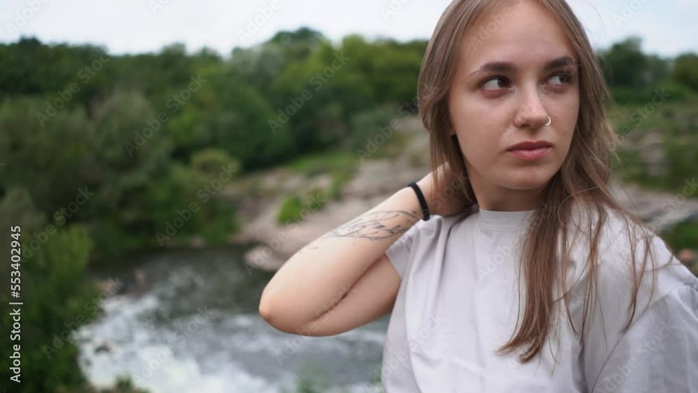 A beautiful girl walks in nature in a green forest with a waterfall and rocks A beautiful girl walks in nature in a green forest with a waterfall and rocks