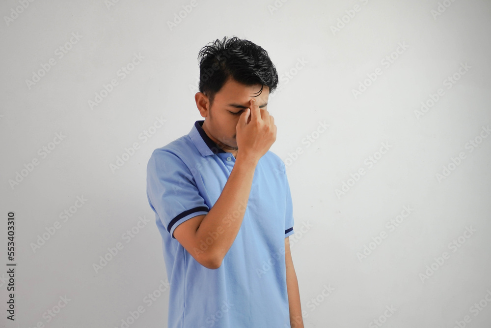 dizziness or depression portrait young asian man holding nose wearing blue polo t shirt isolated on white background dizziness or depression portrait young asian man holding nose wearing blue polo t shirt isolated on white background