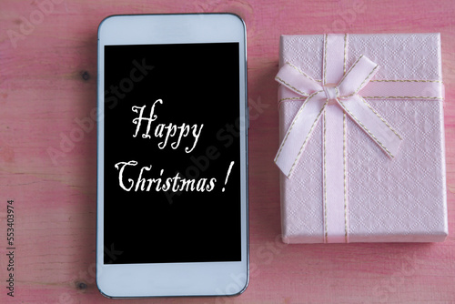 mobile phone and gift box with christmas greeting