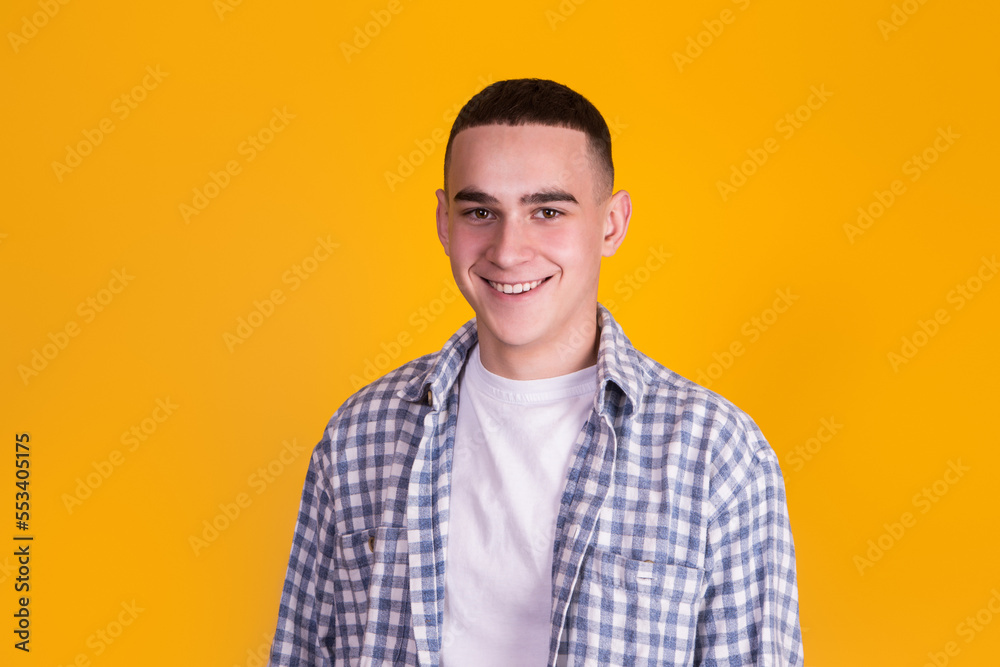 A handsome guy in a checkered shirt on a yellow background A handsome guy in a checkered shirt on a yellow background