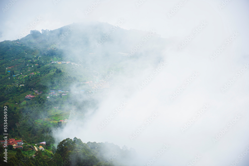 South Indian hill station aerial view and covered with fog during the morning time with hills , trees and plants around it. Kodaikanal hiils station tourist view point Tamilnadu hills and tourism..