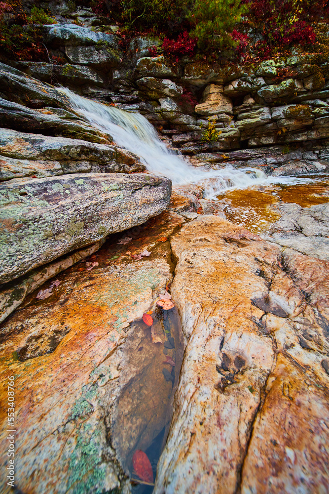 View of rocks in riverbed with puddle of water and waterfall in background View of rocks in riverbed with puddle of water and waterfall in background