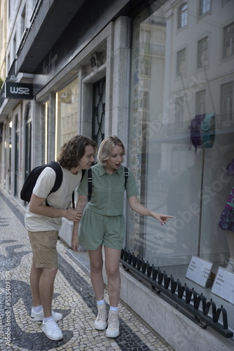 Surprised tourist couple window shopping. Woman pointing at product. Travelling  tourism  romance concept