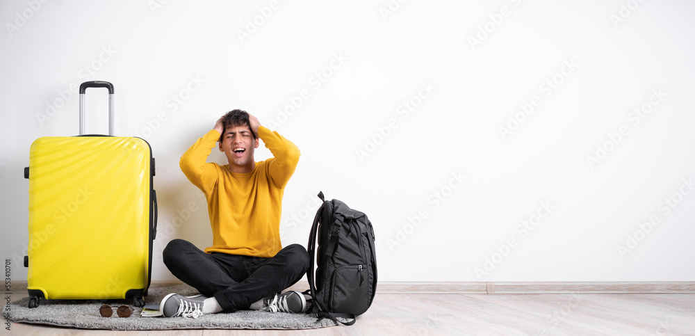 Sick traveler with headache sitting with suitcase over isolated white background having migraine and health problems Sick traveler with headache sitting with suitcase over isolated white background having migraine and health problems