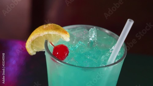 An icy blue cocktail garnished with a lemon wedge and marachino cherry, close up 4K photo