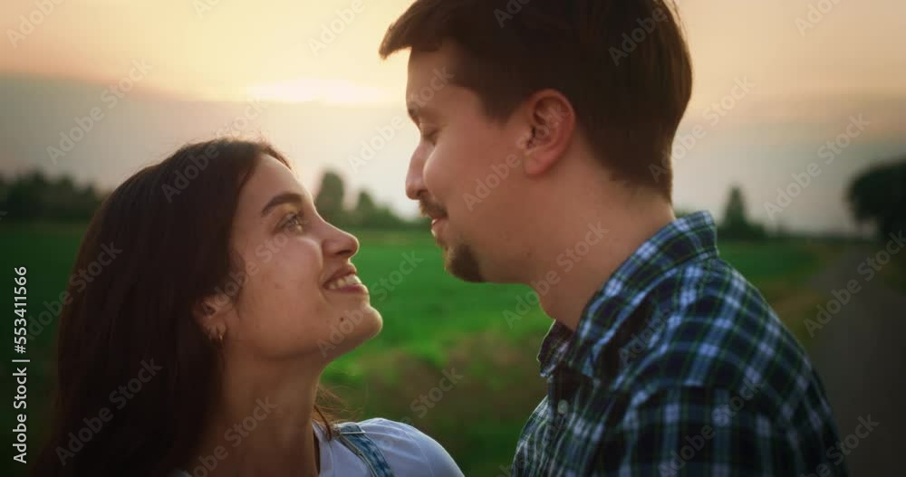 Young Beautiful Couple Hugging and Kissing Outdoors on a Countryside Road with Scenic Green Fields. Relationship Concept with Loving Partners Enjoy Spending Time and Traveling Together. Young Beautiful Couple Hugging and Kissing Outdoors on a Countryside Road with Scenic Green Fields. Relationship Concept with Loving Partners Enjoy Spending Time and Traveling Together.