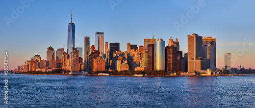 Panoramic golden hour skyline of southern Manhattan New York City skyline from ferry with water in front