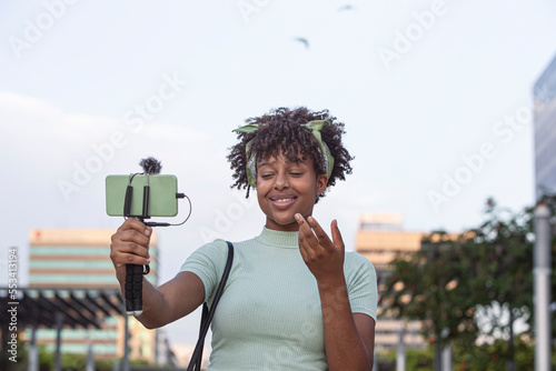Portrait of a young African American woman streaming live on her smartphone while walking through the city. young blogger concept, copy space.