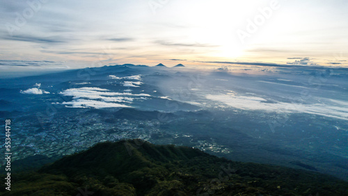 Panorama of flowing fog waves on mountain tropical rainforest, image over the clouds Amazing nature background with clouds and mountain peaks in Purbalingga. 
