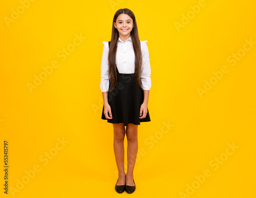School uniform. Teenager child girl casual clothes posing isolated on yellow background in studio. Kids lifestyle concept. Mock up copy space.