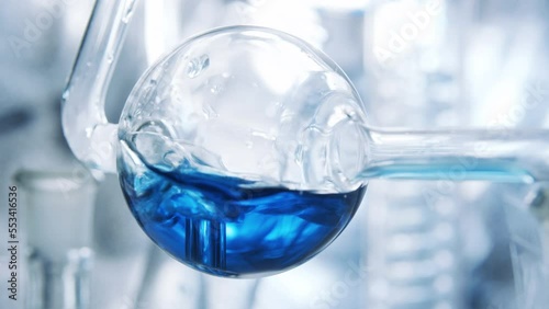 Spherical flask. Boiling and air bubbles in water. Blue liquid in glass of  flask.  Cosmetics and perfumes. Extract from ingredients. Aromatherapy. Сlearing process. Boiling.