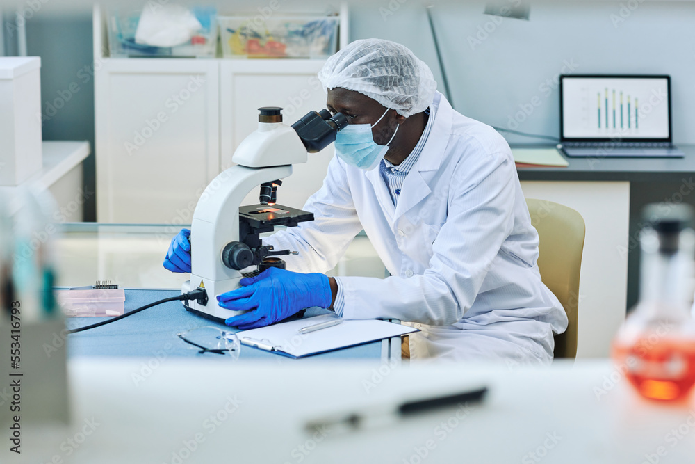 Side view portrait of black scientist using microscope in medical laboratory, copy space Side view portrait of black scientist using microscope in medical laboratory, copy space