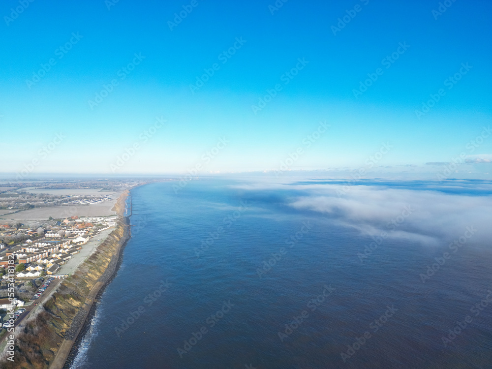 Large fog bank seen coming in from the sea and about to engulf a coastal town on the Suffolk coast during winter. Large fog bank seen coming in from the sea and about to engulf a coastal town on the Suffolk coast during winter.