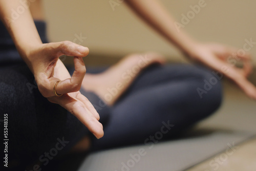 Woman practicing yoga lesson, breathing, meditating, doing Ardha Padmasana exercise, Half Lotus pose with mudra gesture, working out, indoor close up. Well being, wellness concept. Selective focus.