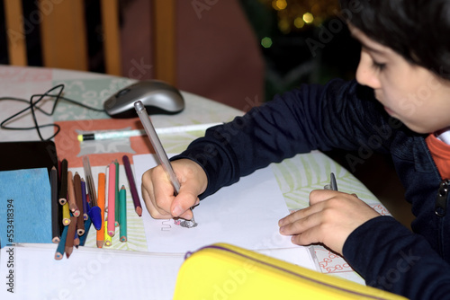 A child drawing and coloring with pens and crayons on a sheet of paper, located in the living room of his house. selective focus. Photograph with space for copy space