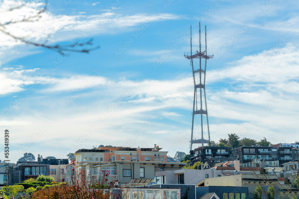 Obraz premium Sutro tower in neighborhood with houses and homes with trees and foliage in the city with blue and white cloudy sky background