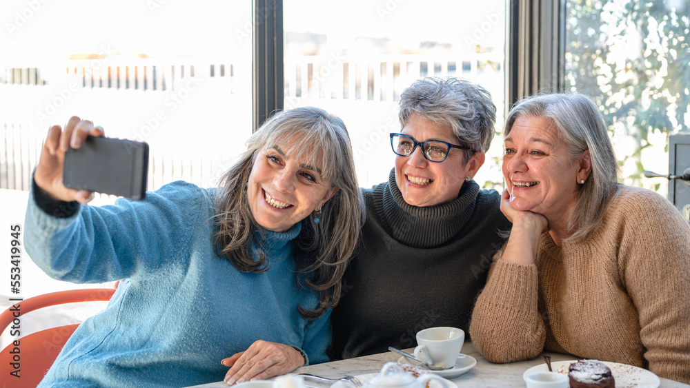 group of elderly women have breakfast in a cafe and enjoy taking photos for social networks, women with gray hair, senior lifestyle