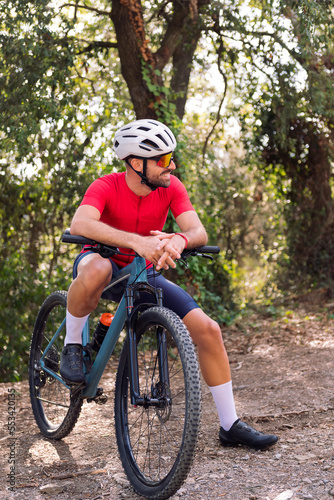 smiling young cyclist resting during his mountain bike training ride, concept of freedom and sport in nature