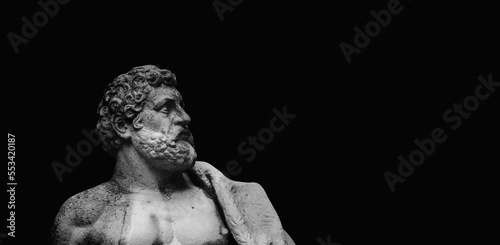 Fragment of an ancient stone statue of Hercules against black backgrouund as symbol of power and strength. Copy space.