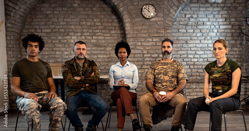 Group of diverse veterans talking during PTSD support group.