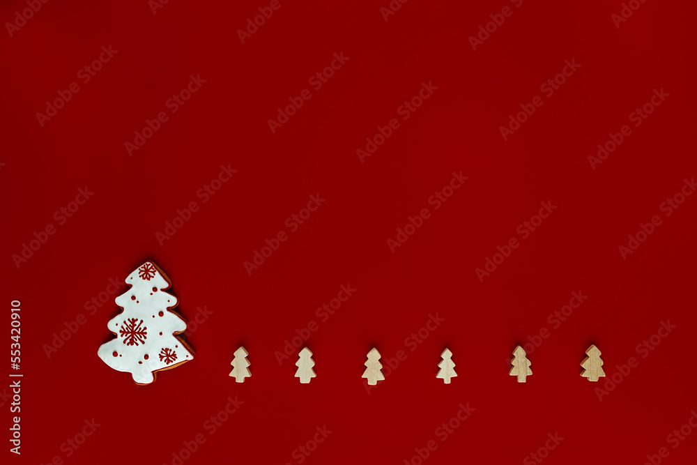 Christmas gingerbread in the form of a Christmas tree and small wooden Christmas trees on a red background . Christmas card  .Place for text
