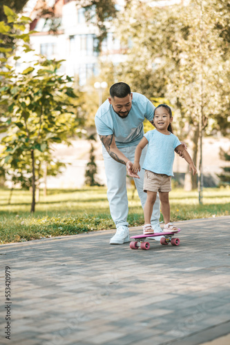 Dad teaching his daughter to ride a skate board
