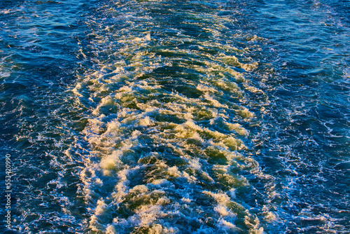 Raging waters from ferry boat looking down on waves with golden light