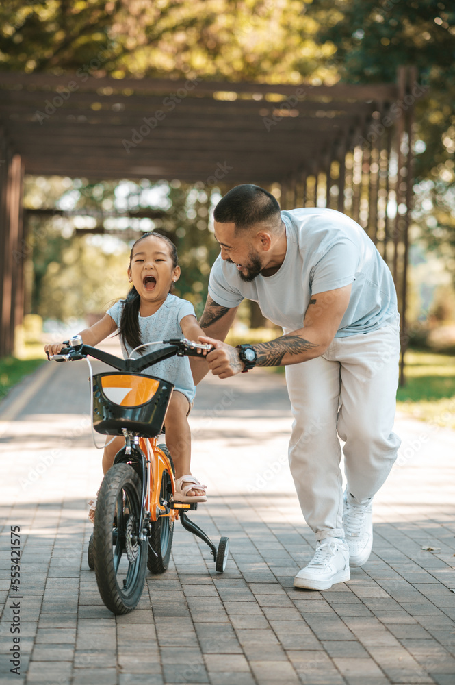 Cute little girl looking excited while riding a bike in the park Cute little girl looking excited while riding a bike in the park