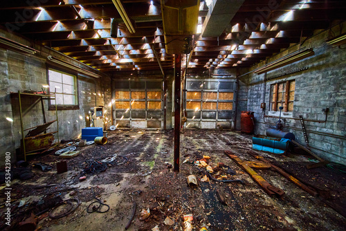 Interior of abandoned double garage mechanic shop with dirty floor and rubble