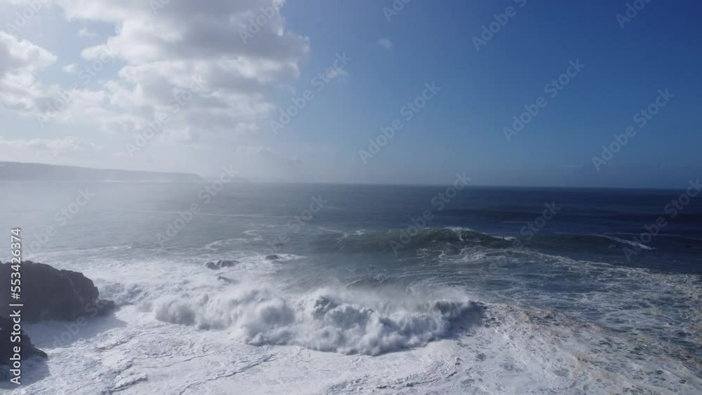 big waves rolling in the bay at praia norte in nazare (portugal), nice sunny weather with jetskies and surfers around big waves rolling in the bay at praia norte in nazare (portugal), nice sunny weather with jetskies and surfers around