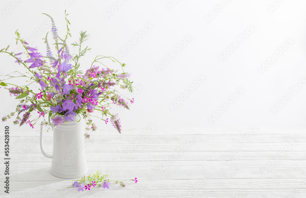 summer wild  flowers  in white jug on white background