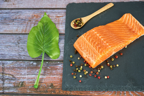 Fresh salmon fillets on black cutting board with herbs and spice
