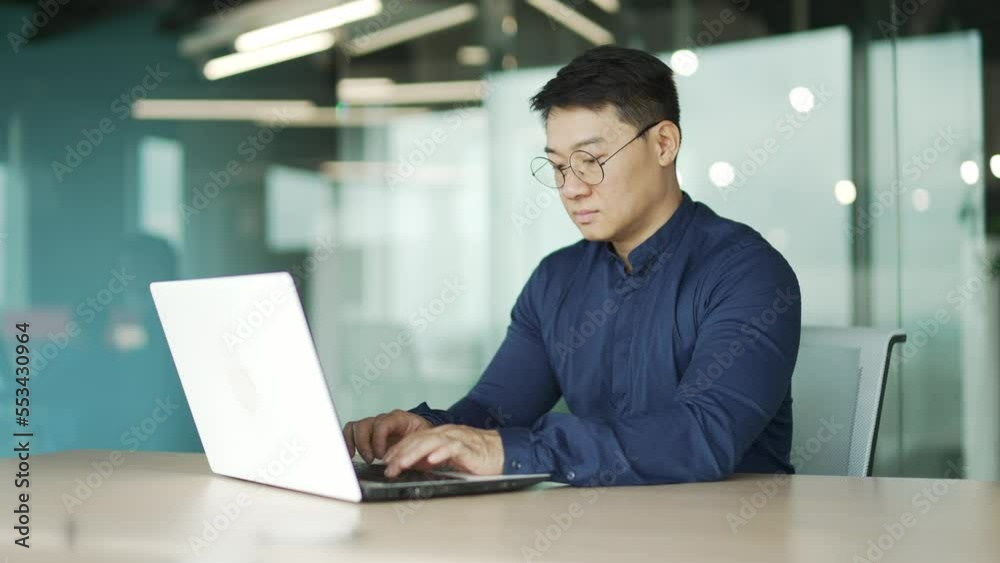 Busy middle aged IT specialist programmer with glasses working typing coding on laptop computer in modern office Asian entrepreneur professional developer thinking analyses finance digital data indoor Busy middle aged IT specialist programmer with glasses working typing coding on laptop computer in modern office Asian entrepreneur professional developer thinking analyses finance digital data indoor