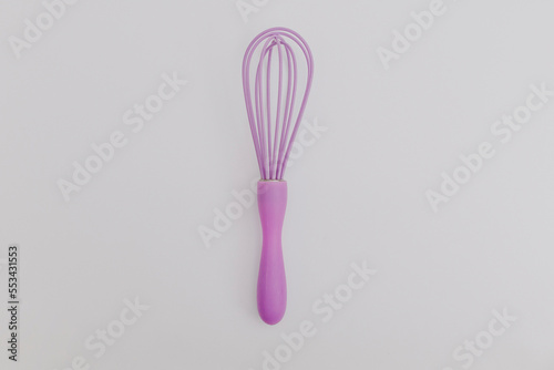 Purple whisk for the kitchen on a white background