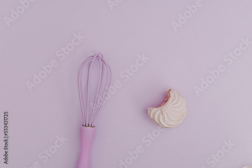 Purple kitchen whisk with marshmallow purple, on purple background