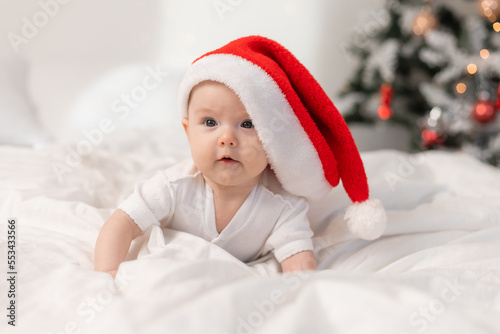 cute baby in Santa hat at home in bed. The first New Year. Christmas Gift